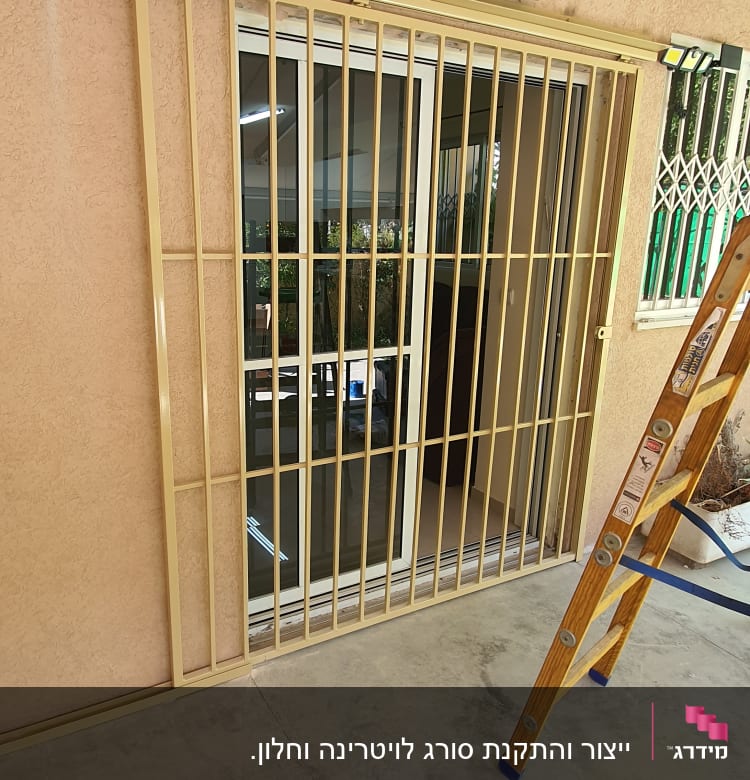 סורג מתכת על חלון זכוכית עם סולם עץ בצד